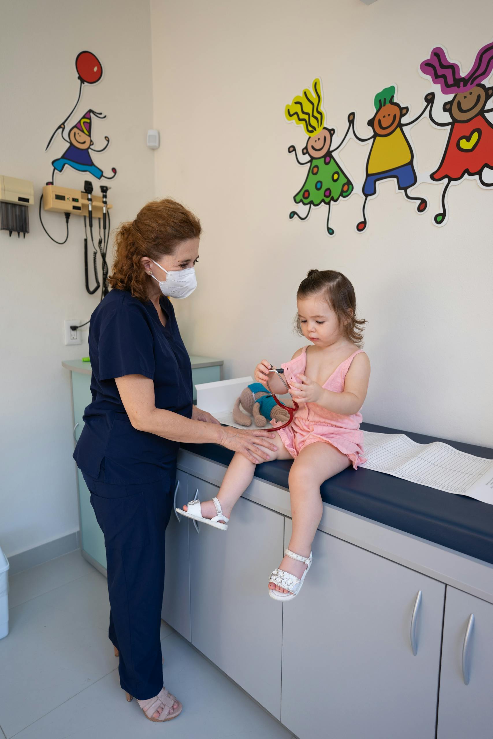 Doctor Standing next to a Little Girl in a Pediatricians Office